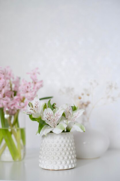 Un jarrón blanco con flores rosas sobre una mesa con jarrones blancos y jarrones blancos.