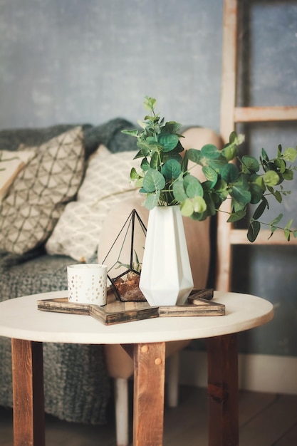 Foto un jarrón blanco con plantas se encuentra sobre una mesa con artículos de decoración para el hogar