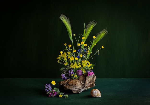 Un jarrón de flores con una concha y un caracol.