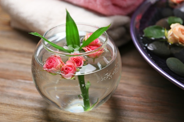 Un jarrón con flores en madera, en el salón de spa