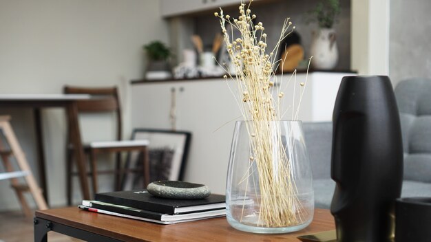 Un jarrón con flores secas sobre una mesa. Habitación clásica escandinava con detalles de madera y blancos, diseño interior minimalista. Foto real. Acogedora casa.