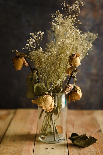 Jarrón con flores secas sobre mesa de madera