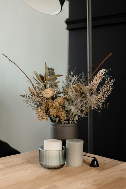 Un jarrón de flores sobre una mesa con un candelabro y una vela blanca.
