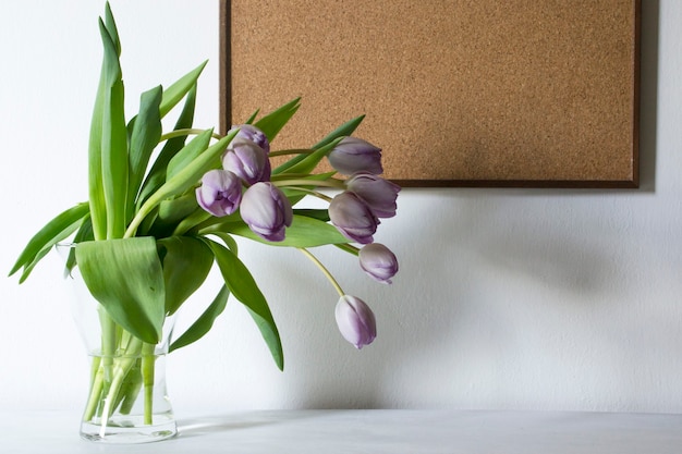 Jarrón con flores de tulipán morado y tablero de madera. Copia espacio
