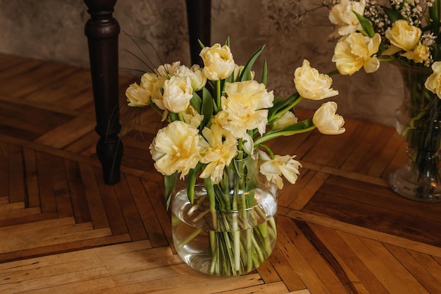 Un jarrón de narcisos amarillos está en el piso al lado de la mesa Flores de primavera en la decoración de la habitación
