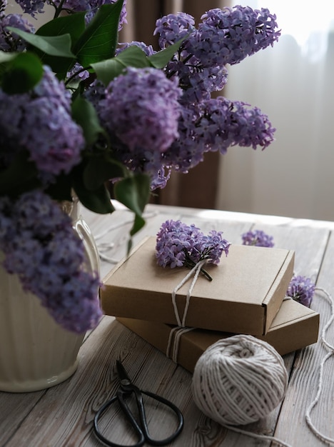 Un jarrón con un ramo de lilas y cajas de regalo artesanales decoradas con flores Idea para envolver regalos