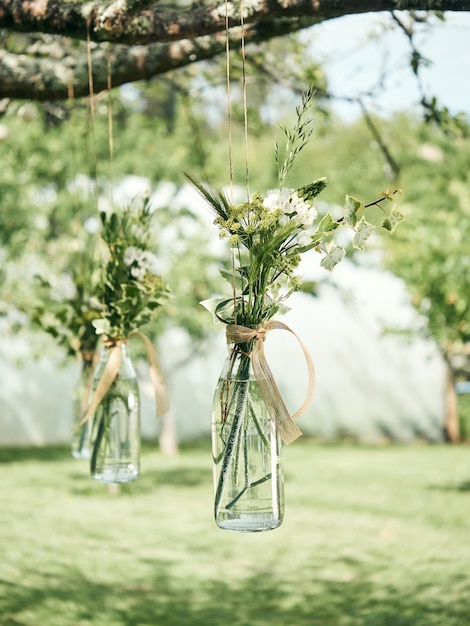 Jarrones de flores colgando de un árbol, concepto de decoraciones de boda