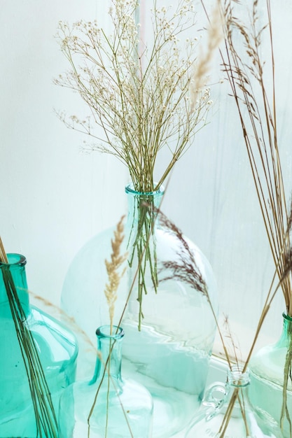 Jarrones de vidrio vintage con hierba seca. Decoración de interiores de moda. Acogedor hogar con plantas esponjosas secas.