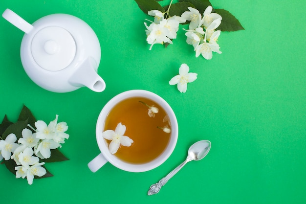 Jasmin grüner Tee in der weißen Tasse auf der grünen Oberfläche