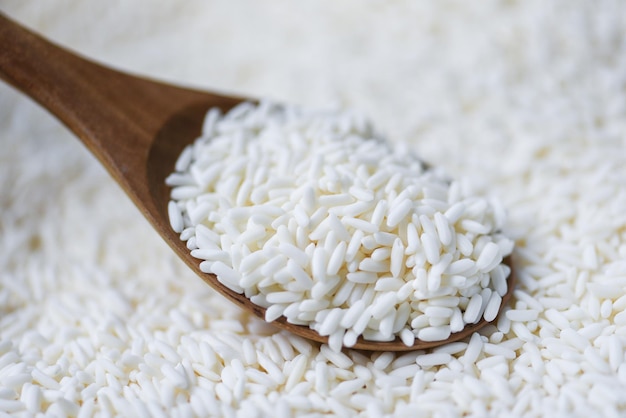 Jasmin weißer Reis auf Holzlöffel im Sack, Erntereis und Lebensmittelkörner Kochkonzept