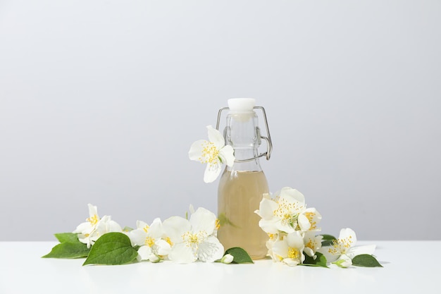 Jasminblüten und Glasflasche auf hellem Hintergrund