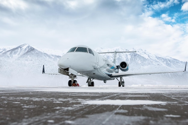 Jato executivo de luxo no avental do aeroporto de inverno no fundo de altas montanhas panorâmicas