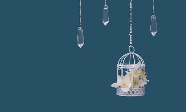 Jaula decorativa con flores de jazmín y colgantes de cristal con cadenas sobre fondo turquesa. Hermoso concepto de boda festiva