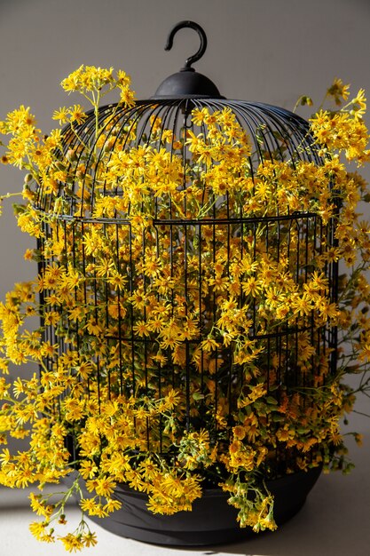Jaula de pájaros con flores amarillas para decoración del hogar.