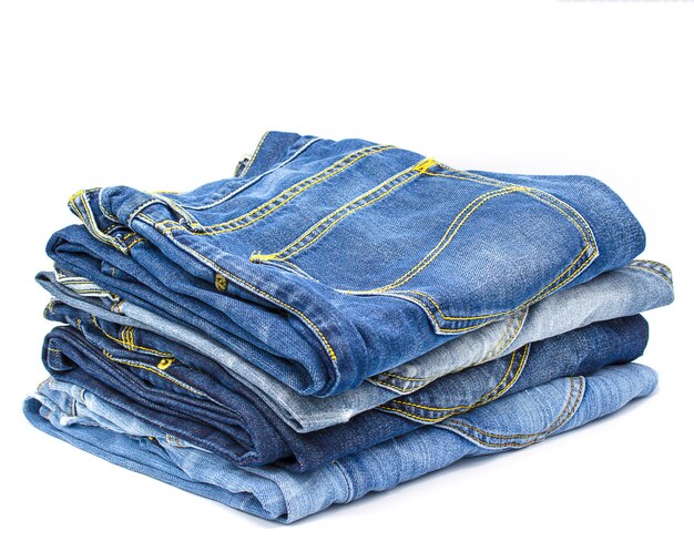 Jeans apilados sobre fondo blanco con espacio de copia.