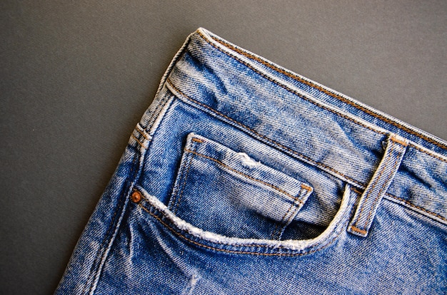 Jeans auf einem schwarzen Tisch. Jeanselemente, Taschen, Nähte in Nahaufnahme. Zerrissene Jeans.