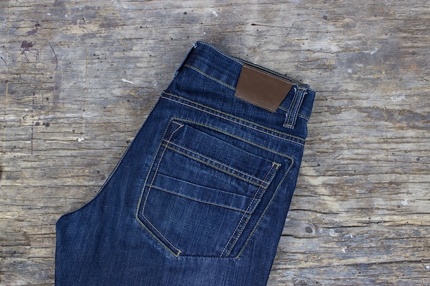 Jeans auf Holzhintergrund, flach. Moderne Kleidung.