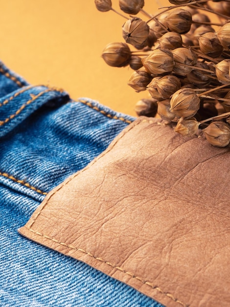 Jeans azul com uma etiqueta em branco de couro marrom e closeup de linho seco Textura de jeans Fundo de jeans de moda para espaço de cópia de costura Etiqueta em roupas para indicar a empresa de tamanho