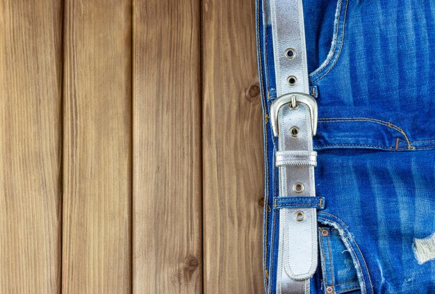 Jeans con cinturón sobre fondo de madera con espacio para texto