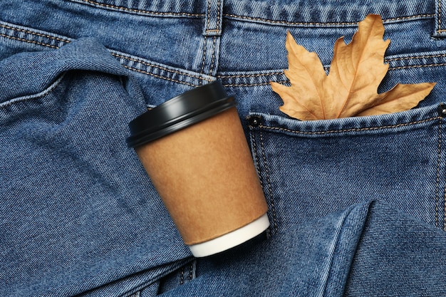 Jeans con hoja en bolsillo y vaso de papel, espacio para texto