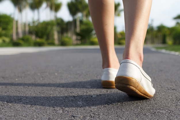 Los jeans de mujer y zapatillas de deporte caminando por la carretera.