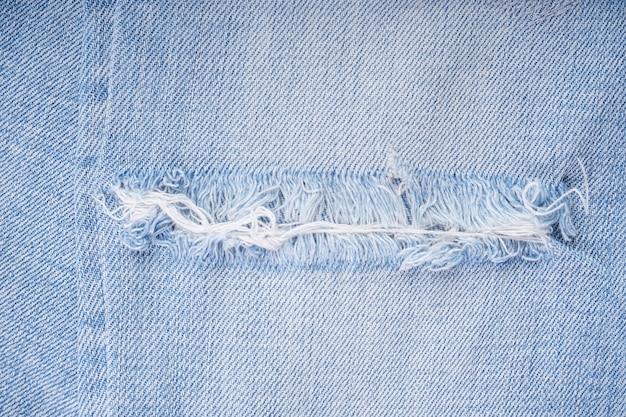 Jeans rasgados com textura de denim azul, calças rasgadas elegantes. calças jeans modernas, close-up.