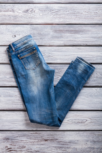 Jeans simples de cor azul. Jeans em fundo cinza de madeira. Melhor mercadoria na loja de jeans. Tecido de qualidade e design simples.