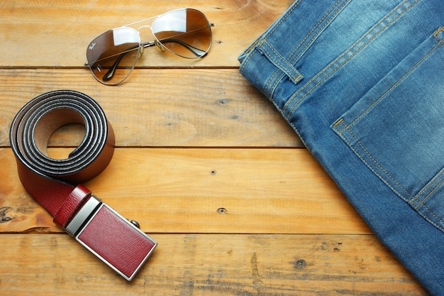 Jeans, Sonnenbrille und Ledergürtel auf der hölzernen Weinlese mit Kopienraum