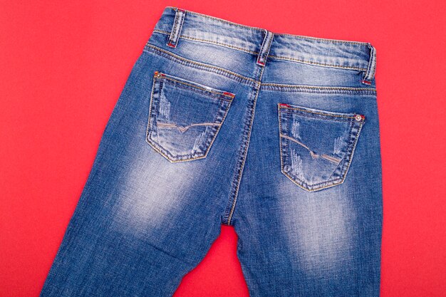 Jeans surrados azul claro em uma superfície vermelha