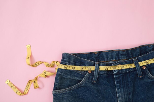 Jeans Taille Messband auf einem rosa Hintergrund