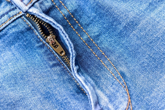 Jeans vorne mit Reißverschluss hellblau Denim Stoff Textur Hintergrund Nahaufnahme selektiver Fokus
