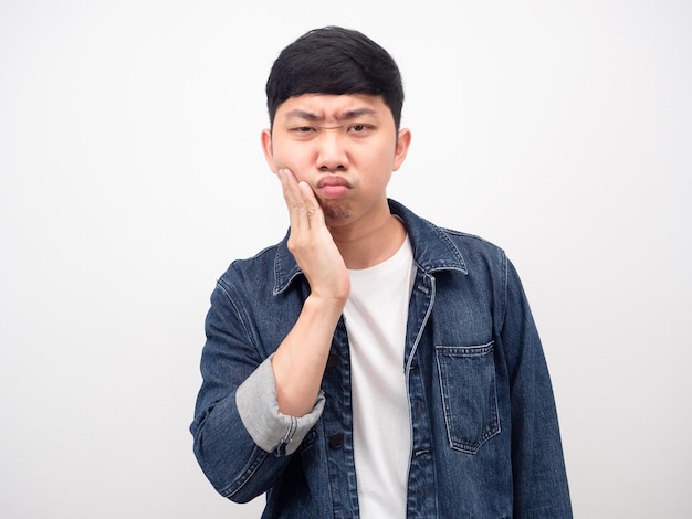 Jeanshemd des asiatischen Mannes, das Zahnschmerzen spürt, berührt seine Wange