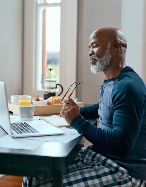 Jederzeit online Aufnahme eines älteren Mannes, der zu Hause einen Laptop verwendet