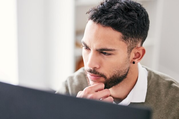 Jedes Problem hat eine Lösung Aufnahme eines hübschen jungen Geschäftsmannes, der allein im Büro sitzt und nachdenklich wirkt, während er seinen Computer benutzt