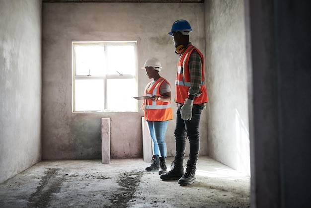 Jedes Zimmer erhält die Fünf-Sterne-Behandlung Aufnahme eines jungen Mannes und einer jungen Frau, die während der Arbeit auf einer Baustelle ein digitales Tablet verwenden