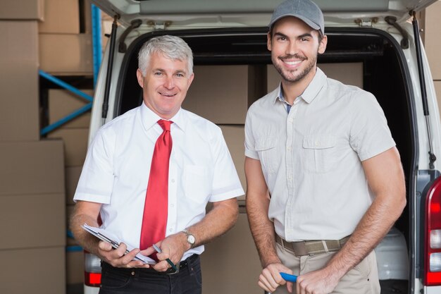 Jefe de almacén y conductor de entrega sonriendo a la cámara