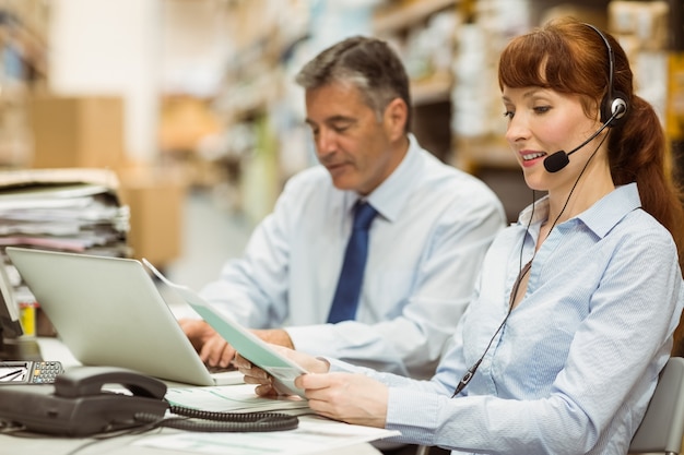 Jefe de almacén trabajando en su escritorio usando auriculares