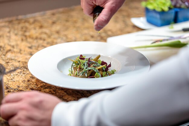 Jefe añadiendo aceite de oliva a una ensalada de verduras