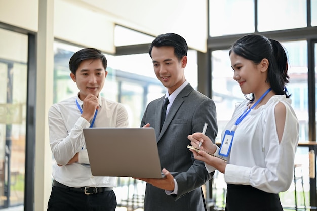 Un jefe asiático profesional revisa los proyectos de sus empleados en una laptop