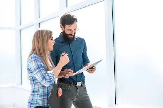 Jefe y asistente discutiendo el horario de trabajo de pie en el pasillo de la oficina entre semana