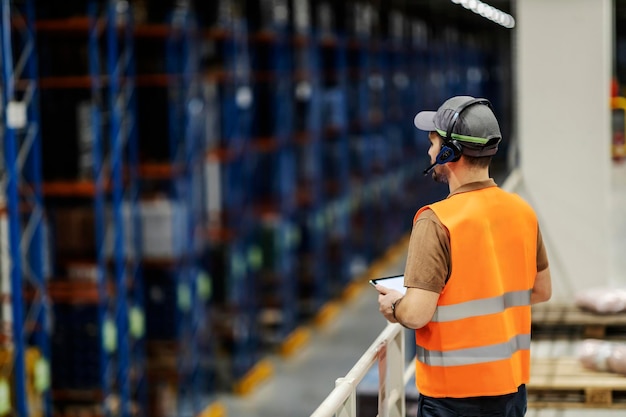 Un jefe con auriculares de recolección de voz y monitoreo de tabletas cargando en el almacenamiento