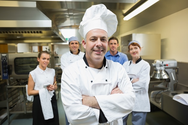 Jefe de cocina posando con el equipo detrás de él