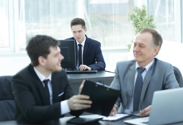 Jefe y empleado discutiendo el documento sentado en el escritorio de la oficina