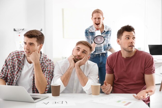 Foto jefe enojado con megáfono gritando a los empleados en la oficina