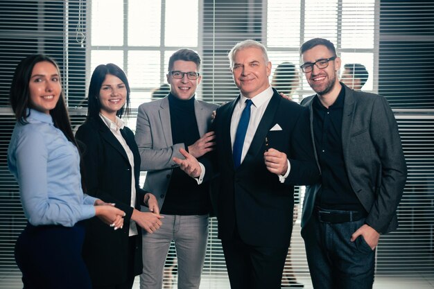 Jefe y equipo de negocios feliz de pie en el vestíbulo de la oficina. el concepto de trabajo exitoso