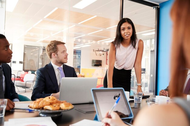 Foto jefe femenino dirigiéndose al equipo en una reunión vista por encima del hombro