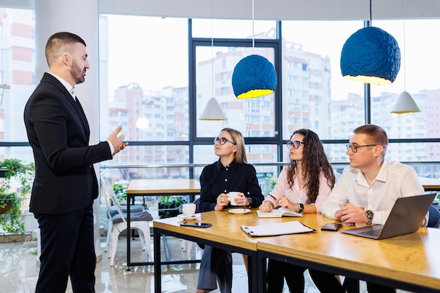 El jefe se para con los gráficos, demuestra estadísticas, varios miembros del personal asisten a la capacitación, presenta los nuevos productos de la empresa, informa sobre los resultados del trabajo para los socios.