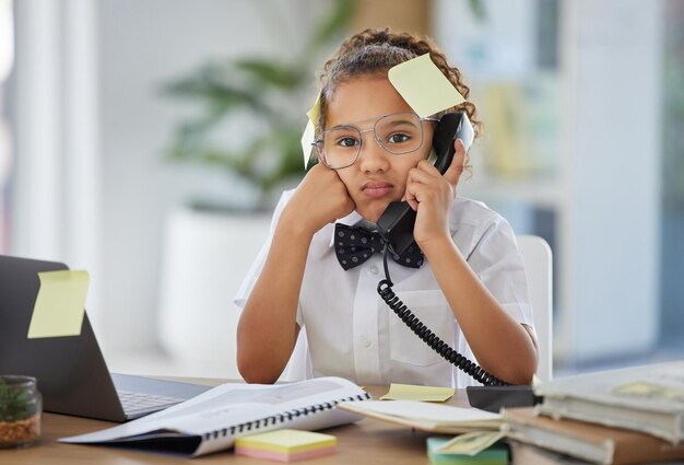 Foto jefe de llamadas telefónicas y niño en un escritorio en la oficina con notas adhesivas y una cara de estrés molesto y molesto teléfono fijo de frustración y director ejecutivo de niña en un teléfono mientras trabaja en un lugar de trabajo moderno