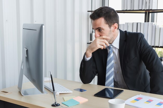 El jefe de negocios está estresado por los tratos comerciales mientras conversa en la tableta de la computadora. Un hombre de negocios haciendo hincapié en el trabajo en una tableta en la oficina.
