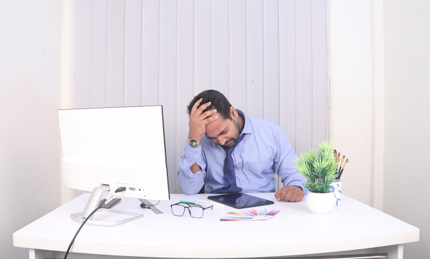 El jefe se puso la mano sobre la cabeza sentado frente al escritorio.